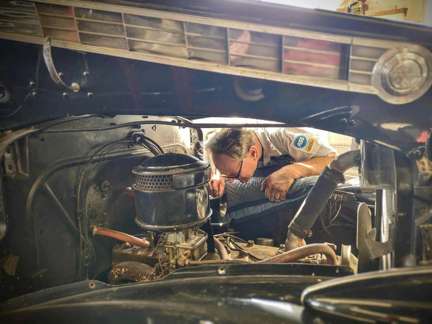 Person working on an old car engine in a garage